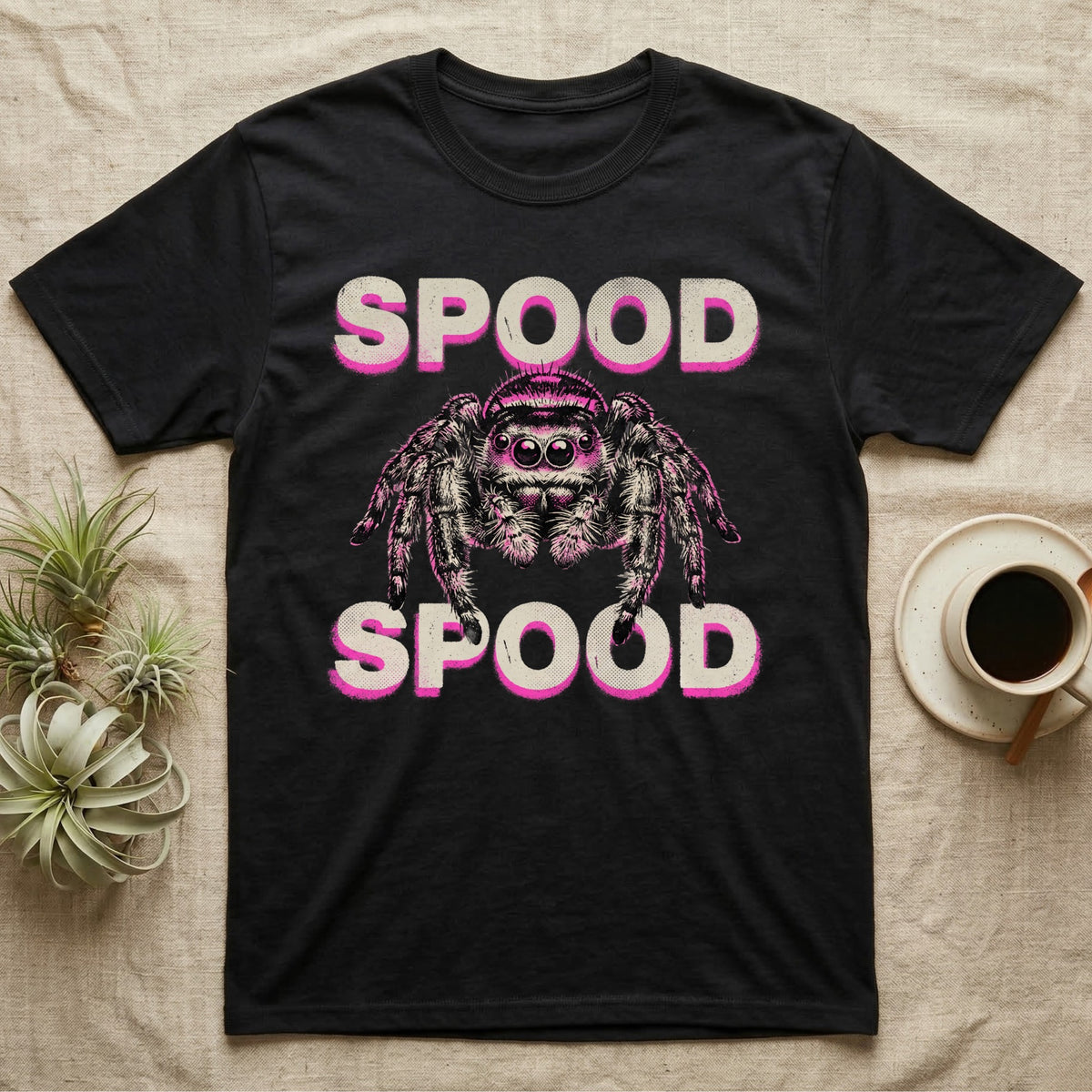 Spood Jumping Spider T-Shirt in Black — Grunge-punk illustration of an oversized front-facing jumping spider with a distressed "Spood" wordmark in bone and acid pink.