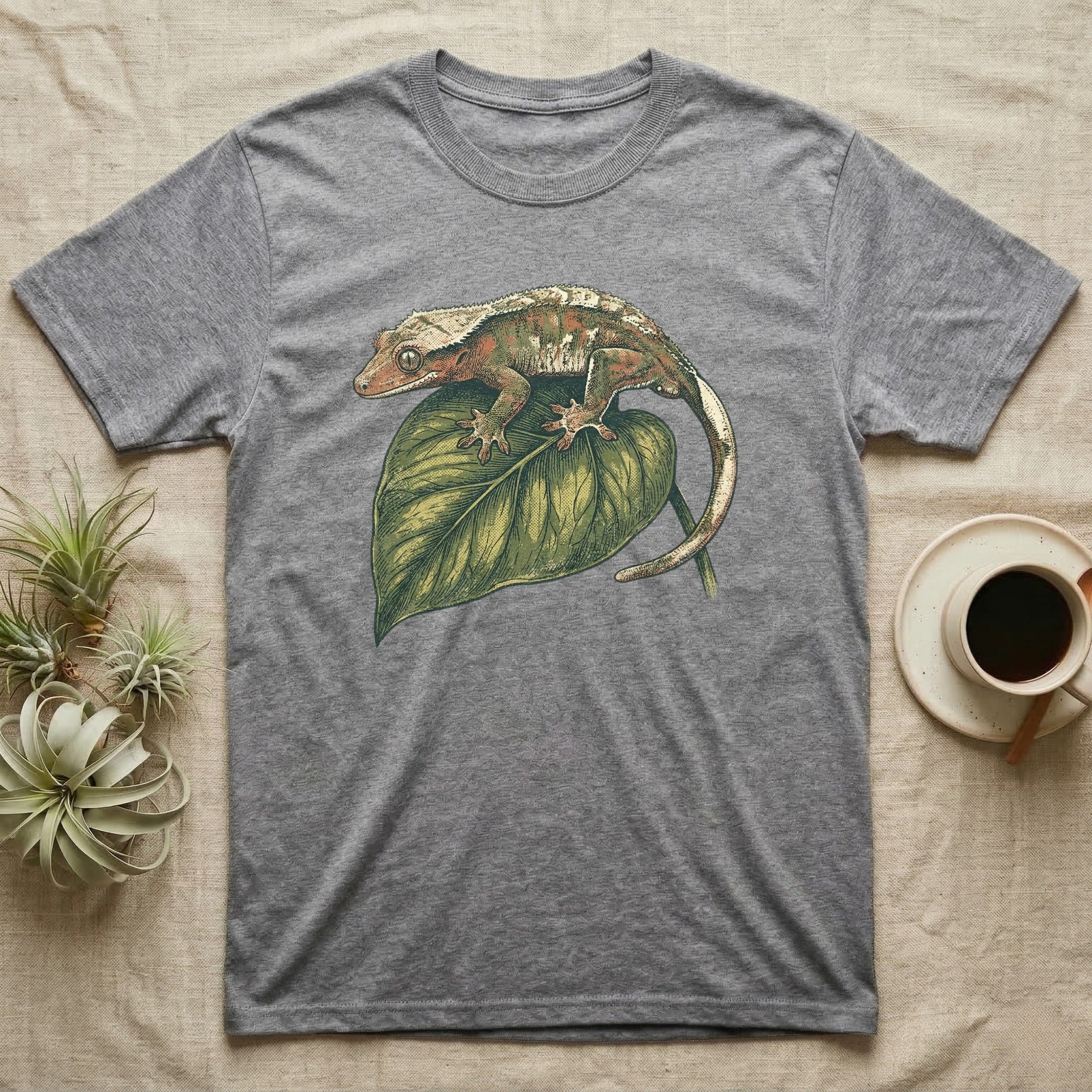 Grey t-shirt with a gecko on a green leaf illustration.