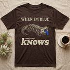 Blue-Tongue Skink Mood T-Shirt in Dark Chocolate — Cream engraved blue-tongued skink on black flashing a cobalt blue tongue under the words WHEN I'M BLUE everyone KNOWS