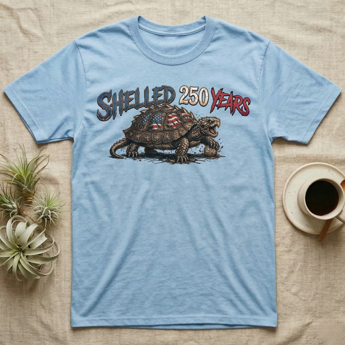 Snapping Turtle 250 T-Shirt in Light Blue — Gritty woodcut alligator snapping turtle with a flag-etched shell on a 250 coin under text Shelled 250 Years.