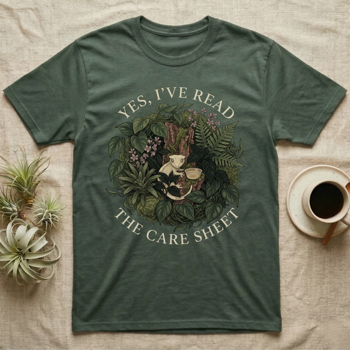 Crested Gecko Care Sheet T-Shirt in Military Green — Botanical wreath of pothos and moss circling a crested gecko, closed by two arcs of Roman capitals.