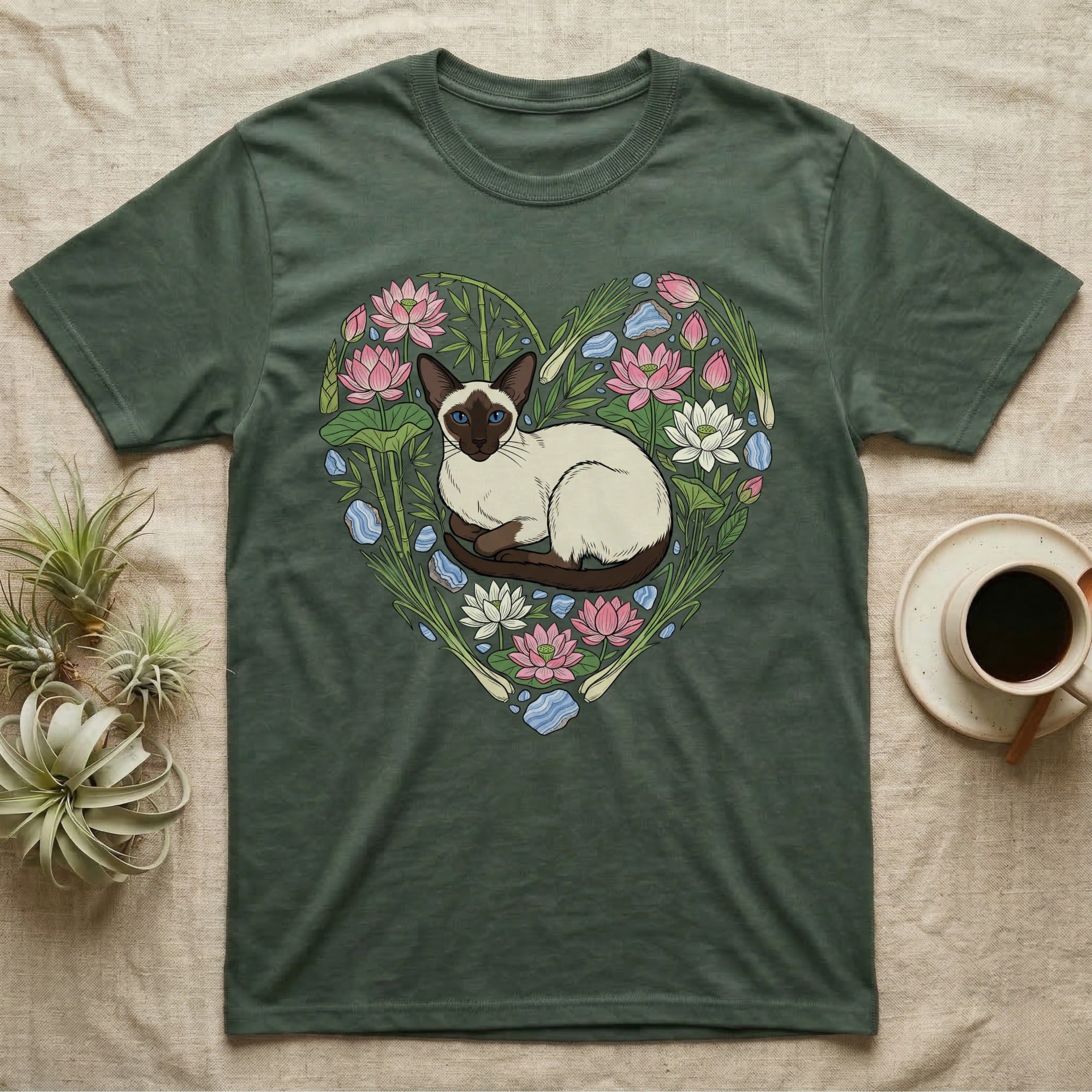 Green t-shirt with Siamese cat illustration surrounded by lotus flowers and water plants.