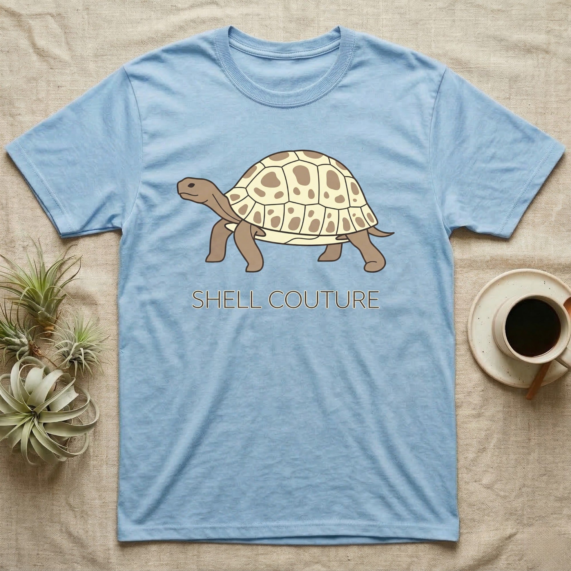Light blue t-shirt with "Shell Couture" and a cartoon tortoise.