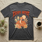 Corn Snake Feral T-Shirt in Dark Heather — Orange corn snake coiled in a pastel cornfield scene under a spiky blood-orange metal wordmark reading ESCAPE ARTIST.