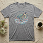 Grey t-shirt with a cartoon sea turtle wearing sunglasses, relaxing.