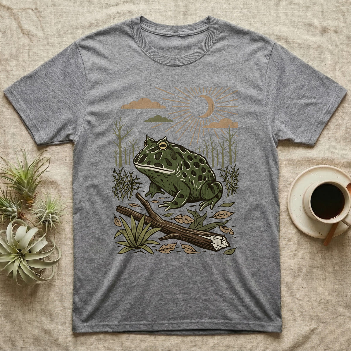 Pacman Frog Home Range T-Shirt in Sport Grey — Woodcut-style illustration of a pacman frog sitting on the Chaco forest floor among fallen branches and thorn scrub, no on-shirt text.