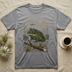 Pacman Frog Home Range T-Shirt in Sport Grey — Woodcut-style illustration of a pacman frog sitting on the Chaco forest floor among fallen branches and thorn scrub, no on-shirt text.