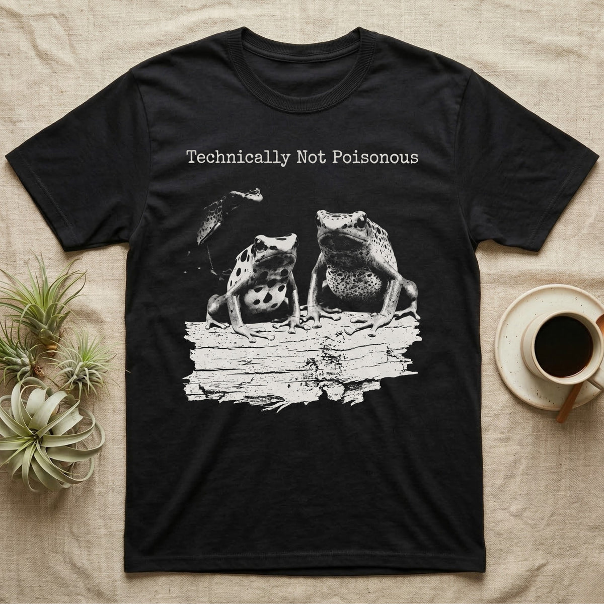 Technically Not Poisonous Dart Frog T-Shirt in Black — Three blue poison dart frogs on a bark ledge in distressed screen-print style under the line Technically Not Poisonous.