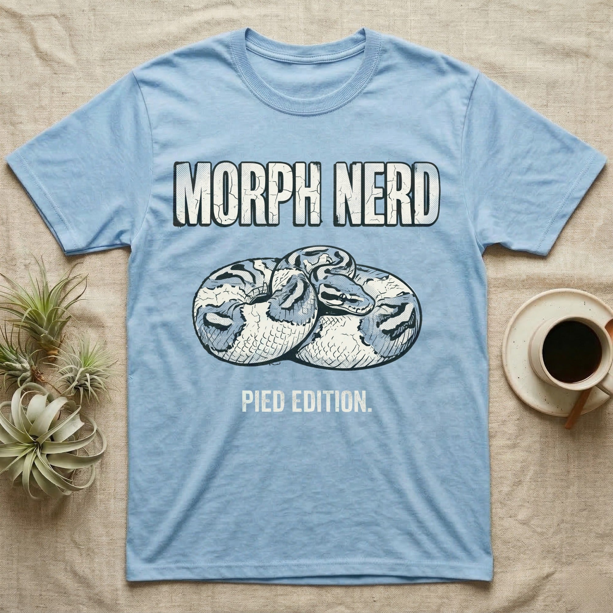 Pied Ball Python Morph T-Shirt in Light Blue — Grunge type "Morph Nerd" with a small pied-morph ball python coiled mid-design and "Pied Edition" caption beneath.