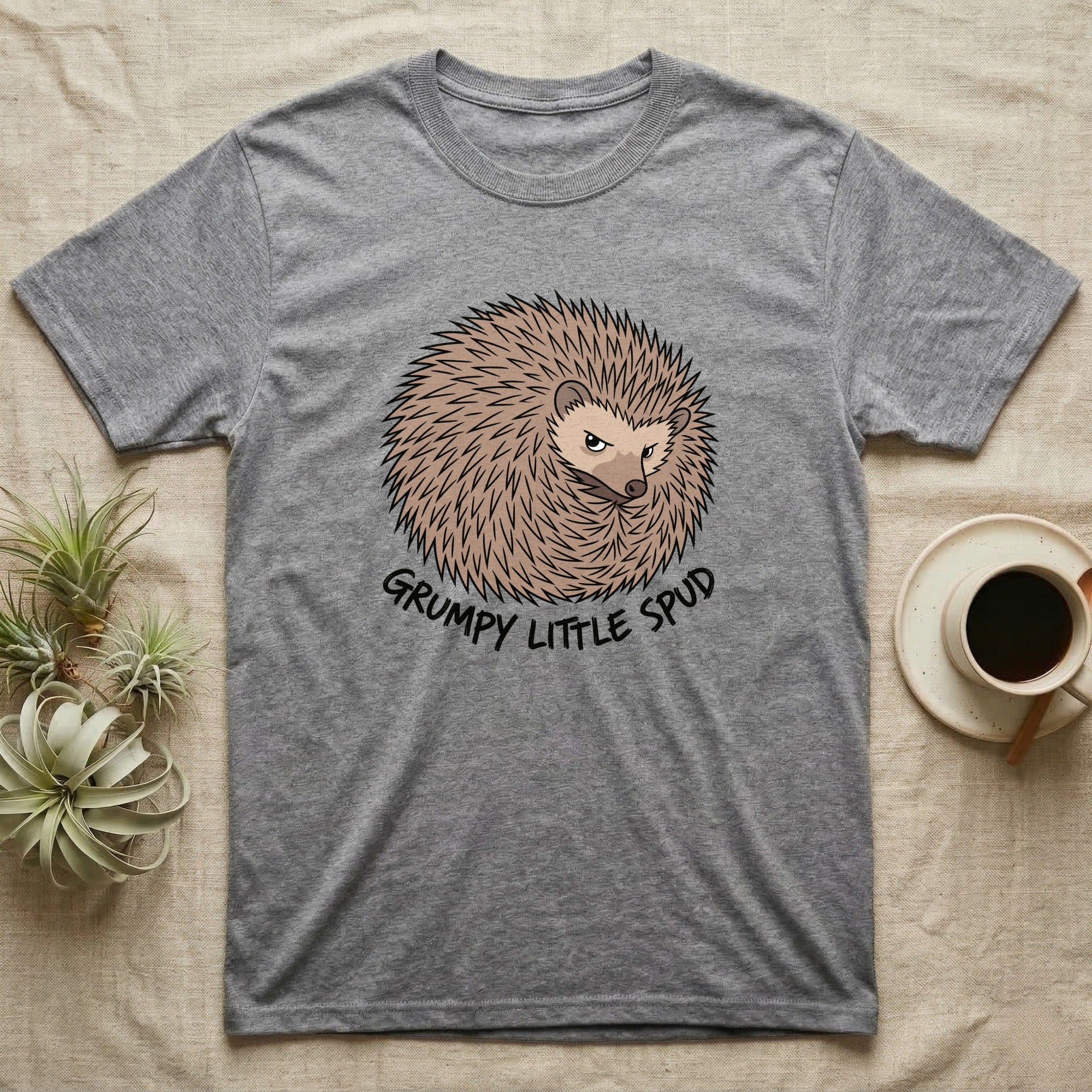Grey t-shirt with a grumpy hedgehog design that says "Grumpy Little Spud".