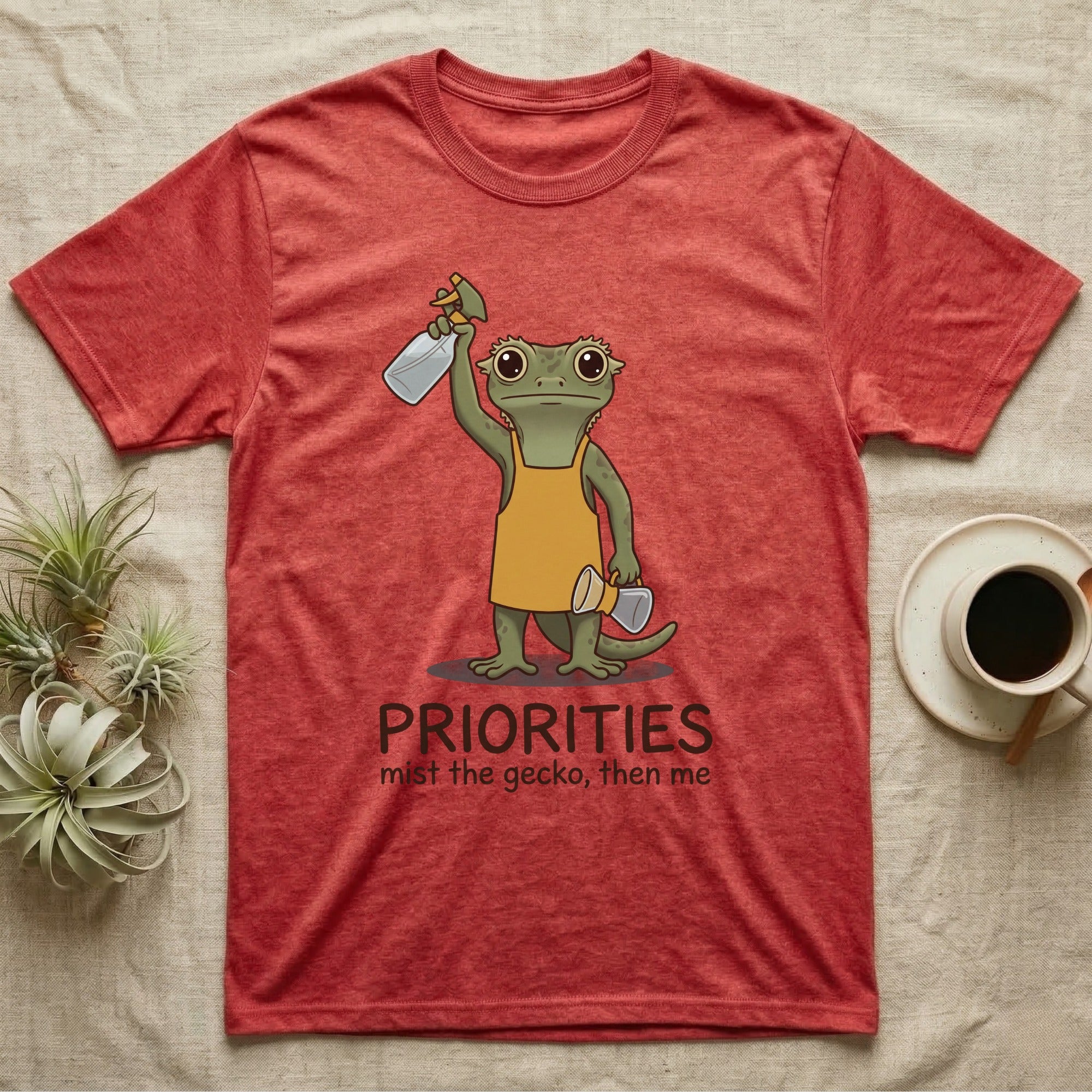 Crested Gecko Coffee T-Shirt in Heather Red — Storybook crested gecko standing with a raised spray mister and a pour-over coffee, text priorities below