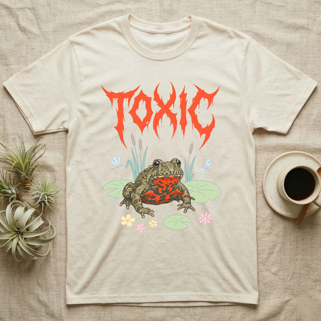 Oriental Fire-Bellied Toad Feral T-Shirt in Natural — Pastel fire-bellied toad with red-orange belly among lily pads and dragonflies, jagged metal wordmark "TOXIC" above.