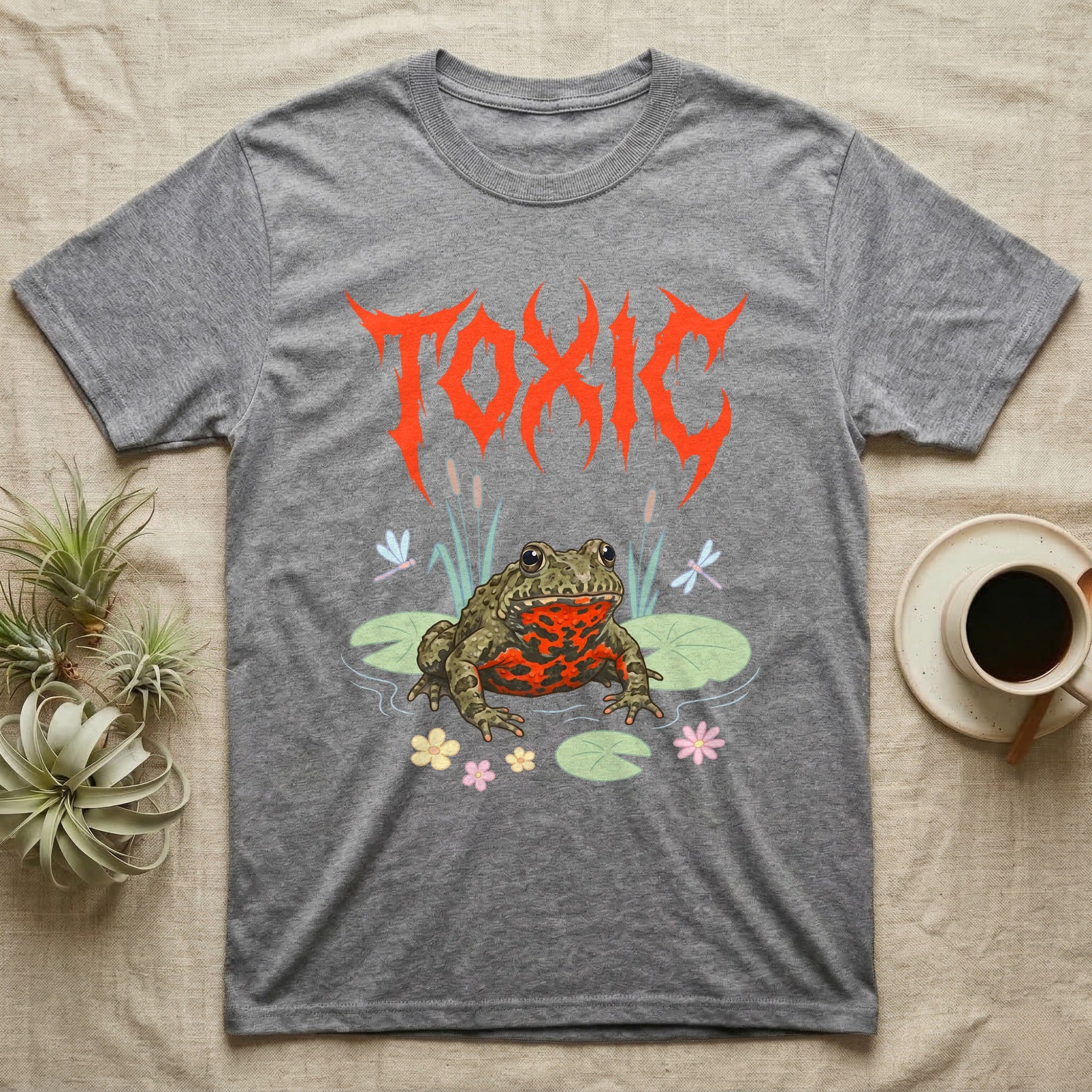 Oriental Fire-Bellied Toad Feral T-Shirt in Sport Grey — Pastel fire-bellied toad with red-orange belly among lily pads and dragonflies, jagged metal wordmark "TOXIC" above.