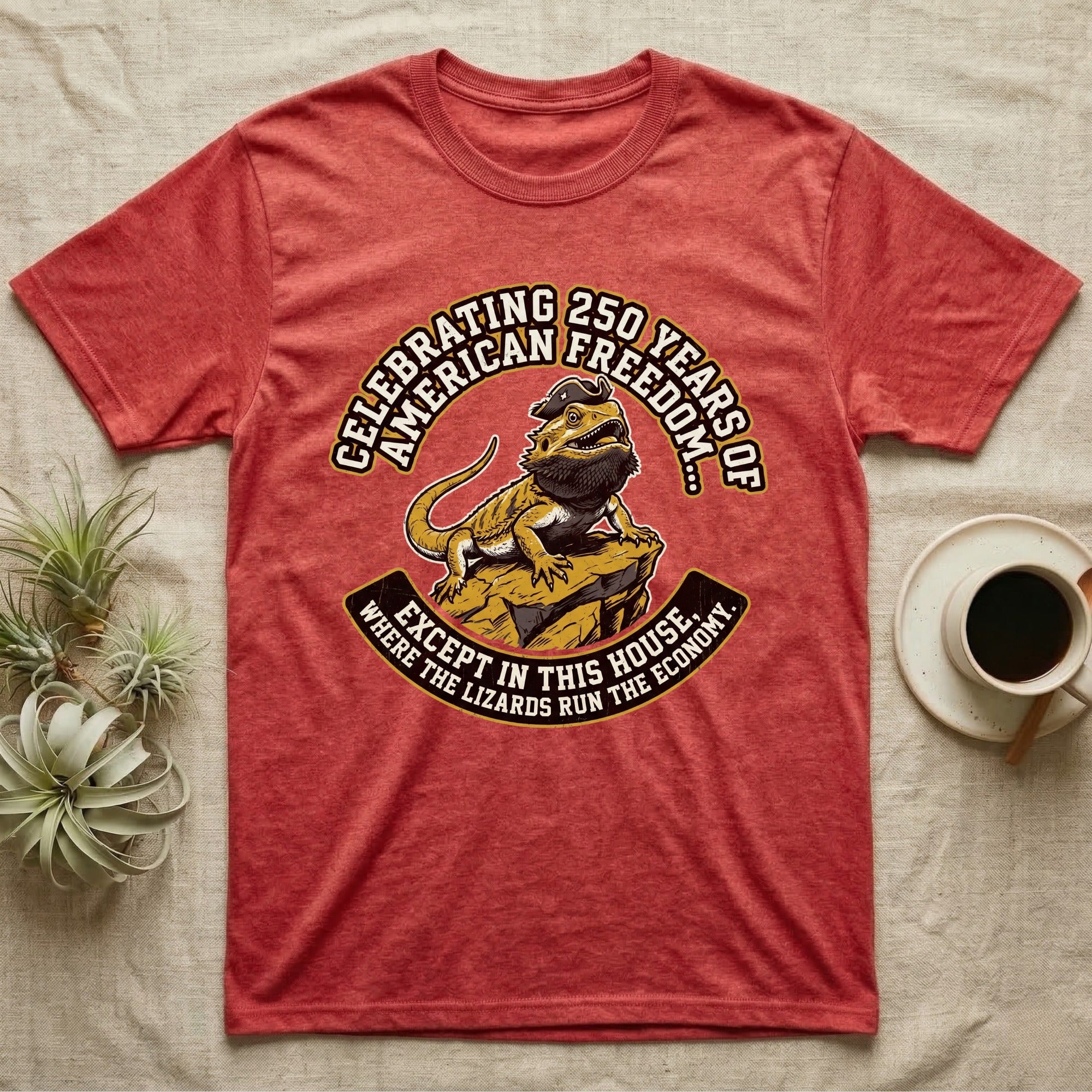 Bearded Dragon 1776 T-Shirt in Heather Red — Bold woodcut tee of a bearded dragon in a tricorn hat black-bearding on a rock, gold and cream banner reading the lizards run the economy.