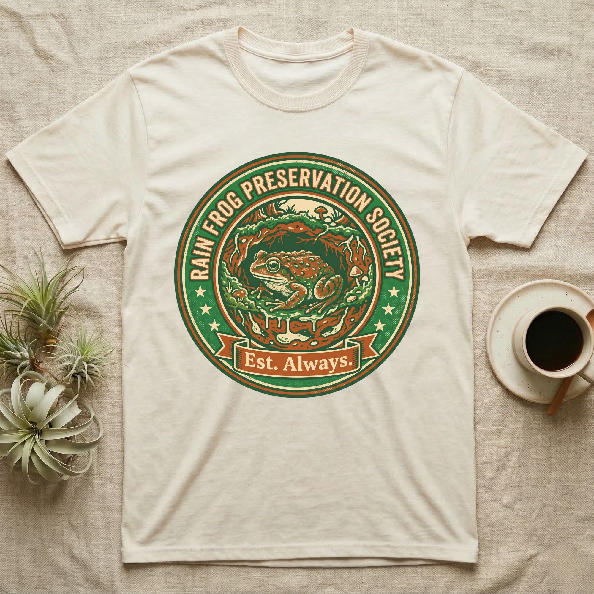Cream t-shirt with a circular logo featuring a frog and "Rain Frog Preservation Society Est. Always."