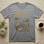 Blue-Tongued Skink Home Range T-Shirt in Sport Grey — Woodcut-style illustration of a blue-tongued skink walking across bare soil with its tongue out, shed skin and grass trees behind, no on-shirt text.