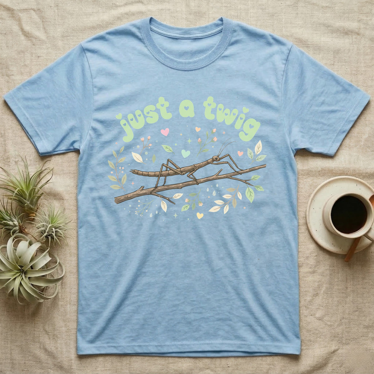 Stick Insect Softie T-Shirt in Light Blue — Camouflaged stick insect on a branch under pastel bubble text "just a twig" with tiny hearts.