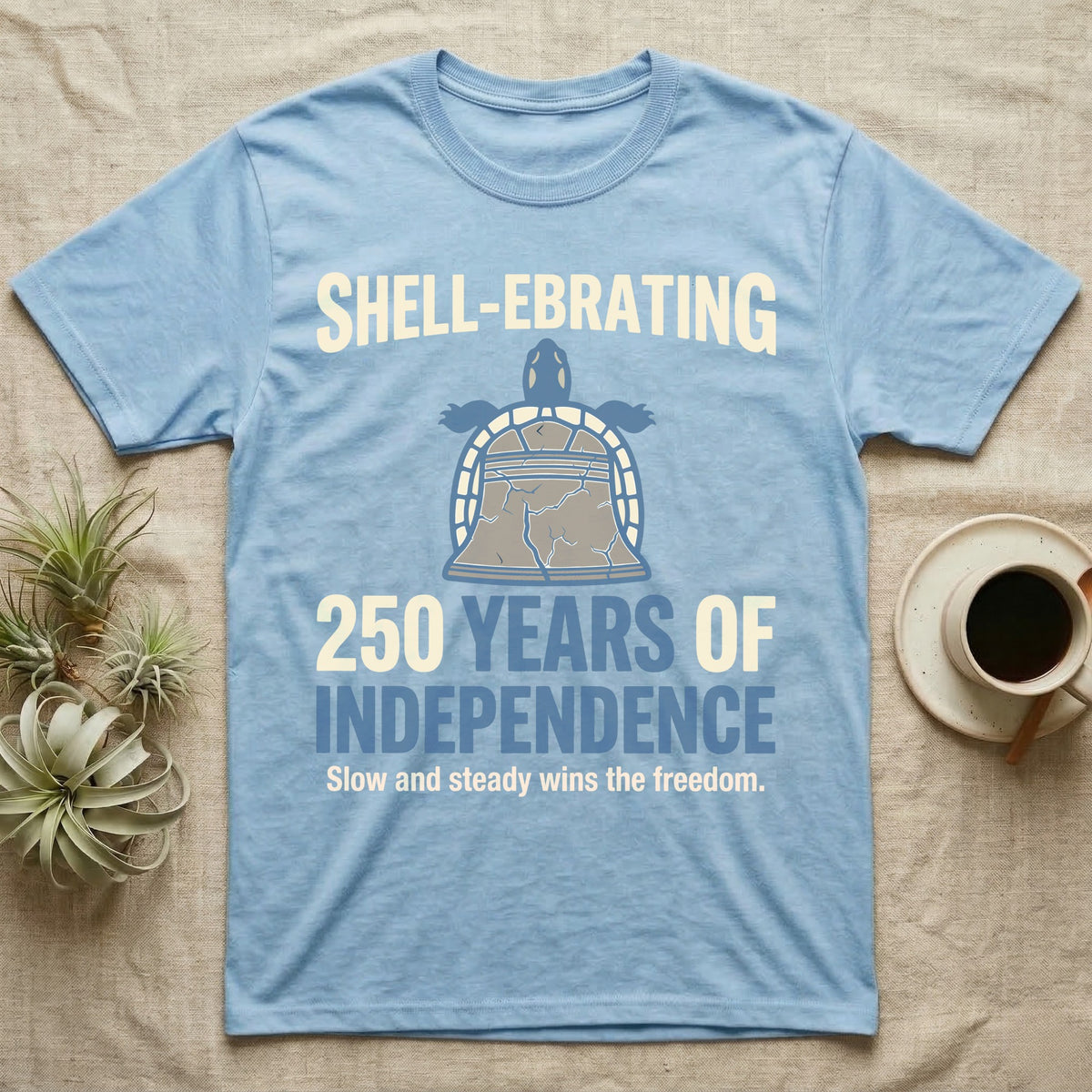 Sea Turtle Liberty Bell T-Shirt in Light Blue — Slate-blue and cream tee of a sea turtle whose shell is drawn as the Liberty Bell under Shell-Ebrating 250 Years text.