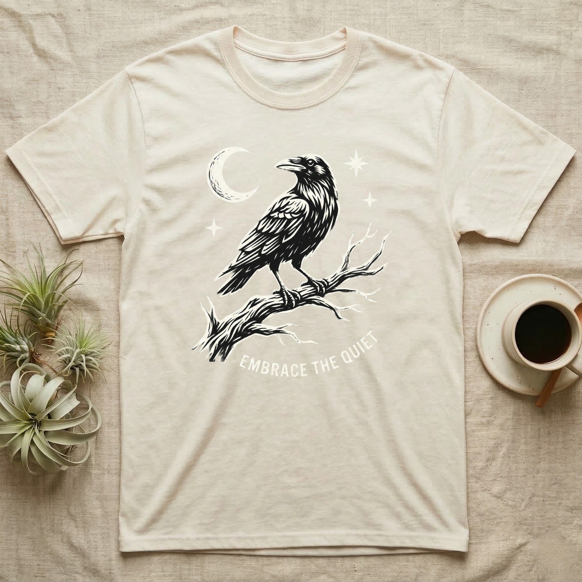 Cream t-shirt with raven illustration and "Embrace the Quiet" text.