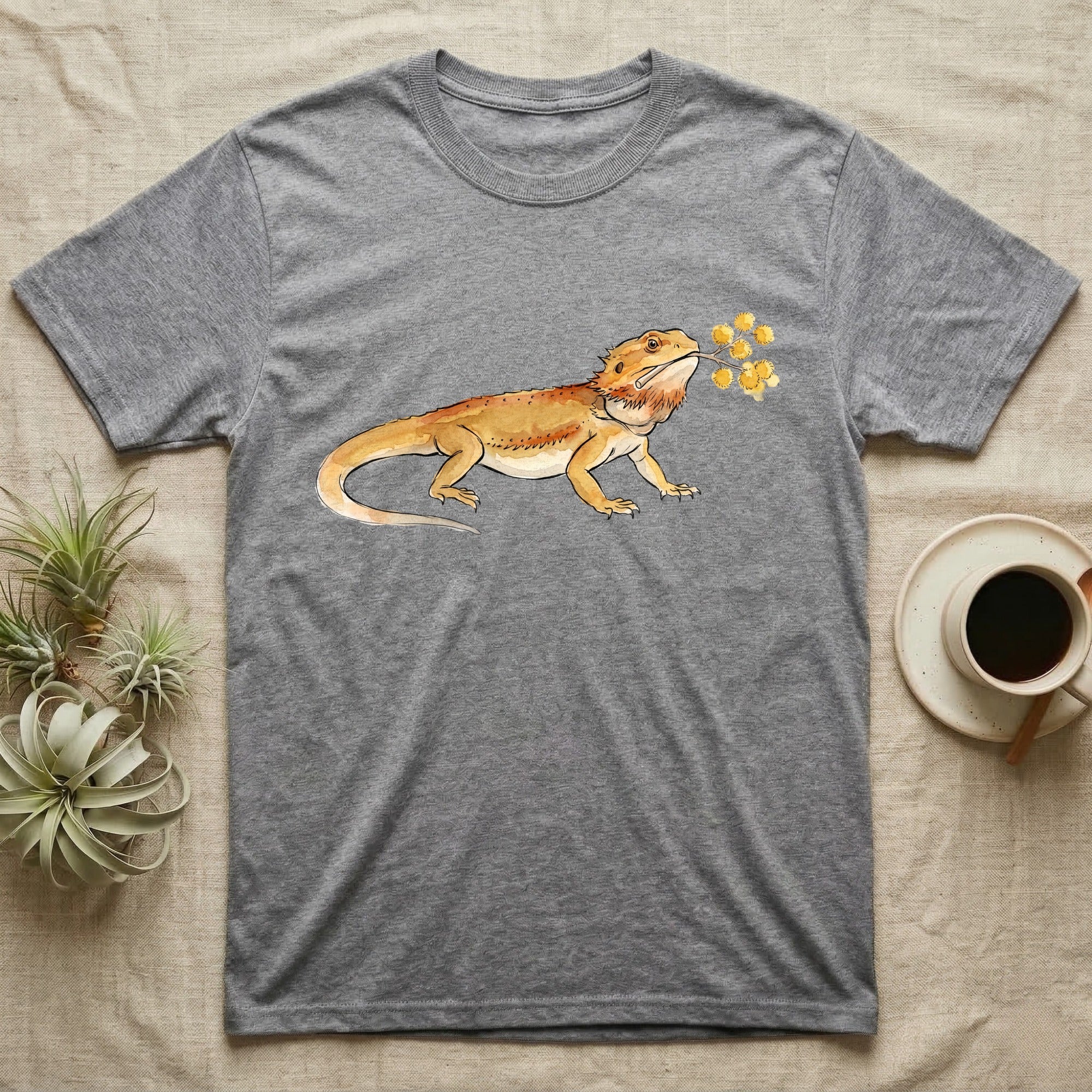 Bearded Dragon Blossom T-Shirt in Sport Grey — Watercolor illustration of an ochre bearded dragon holding a golden wattle blossom sprig, on a dark grey t-shirt.