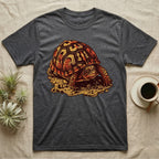 Vintage ink illustration of an Eastern box turtle crawling across sandy pebbles, high-domed shell shown in rust-red and amber, no on-shirt text. — shown on a Dark Heather tee.