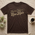 Tortoise Owner Retro T-Shirt in Dark Chocolate — Worn 1970s brush script reading Same Tortoise in tortoise-shell texture over Less Hair in warm sand, climbing a diagonal on charcoal grey
