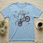 Crested Gecko BMX T-Shirt in Light Blue — Distressed one-ink oxblood screenprint of a crested gecko airborne on a BMX bike mid-barspin, front hands thrown wide, back feet gripping the pedals.