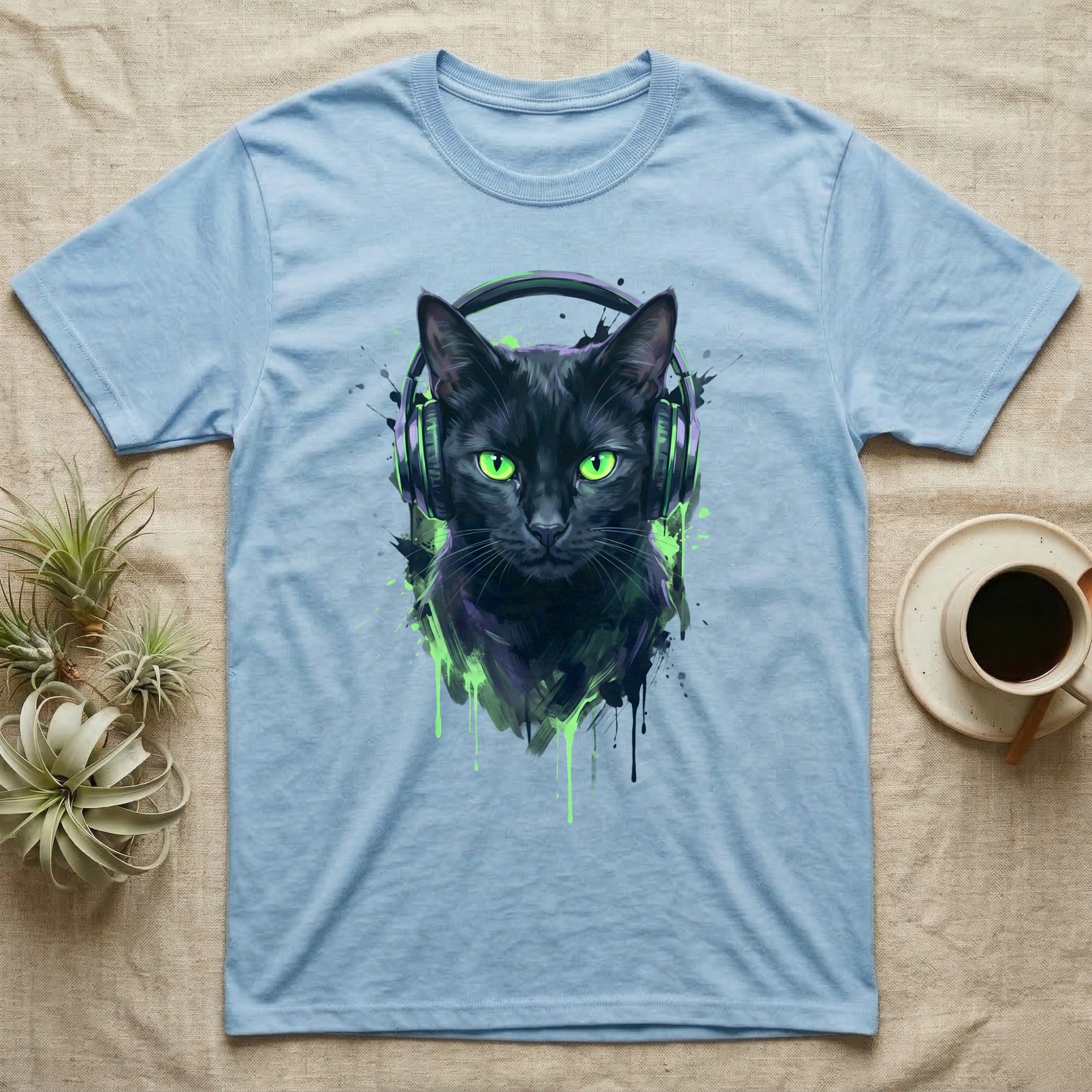 Black cat wearing green headphones, graphic design on light blue t-shirt.