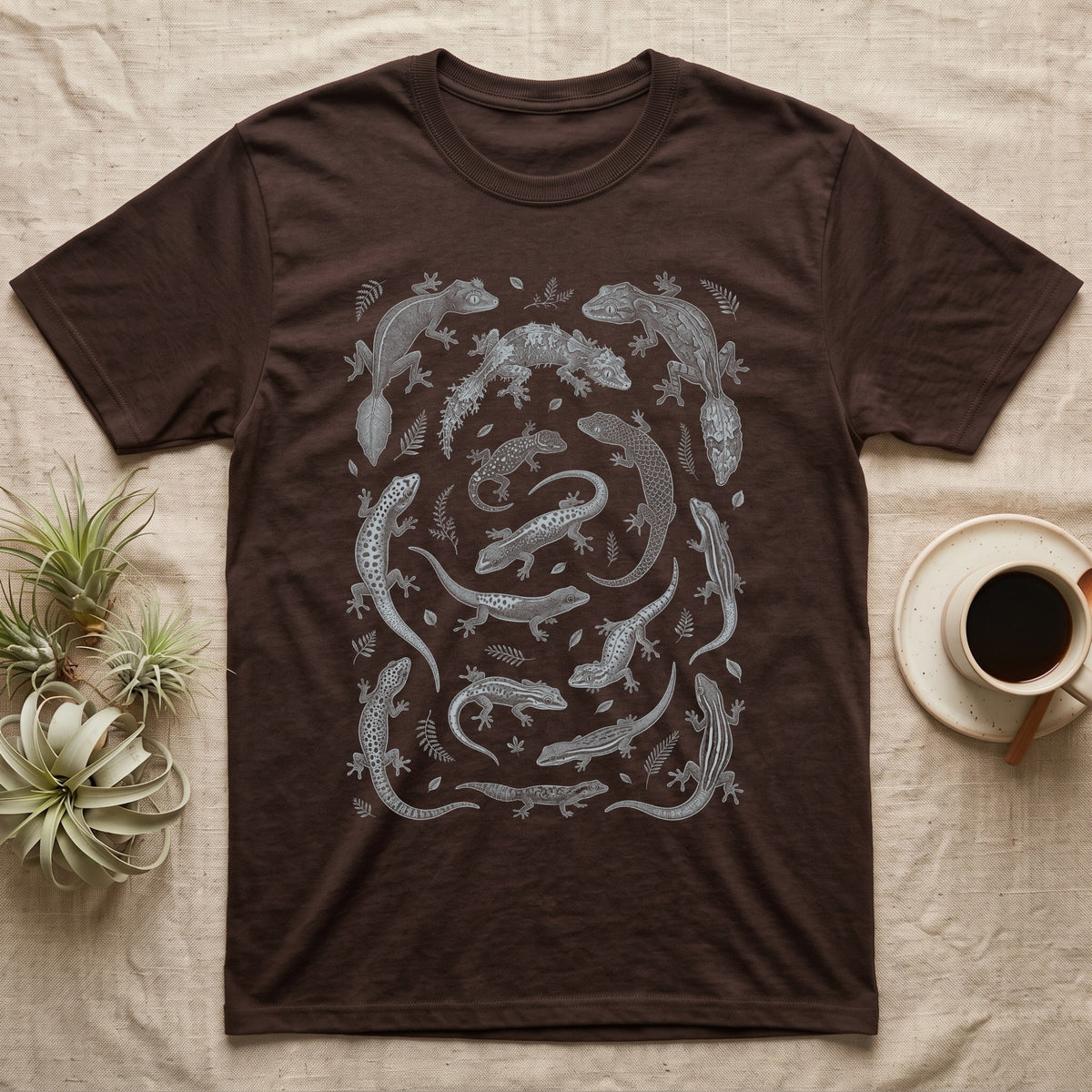 Gecko Specimen Plate T-Shirt in Dark Chocolate — Engraved white-line specimen plate of fifteen Madagascan geckos and fern sprigs on charcoal grey