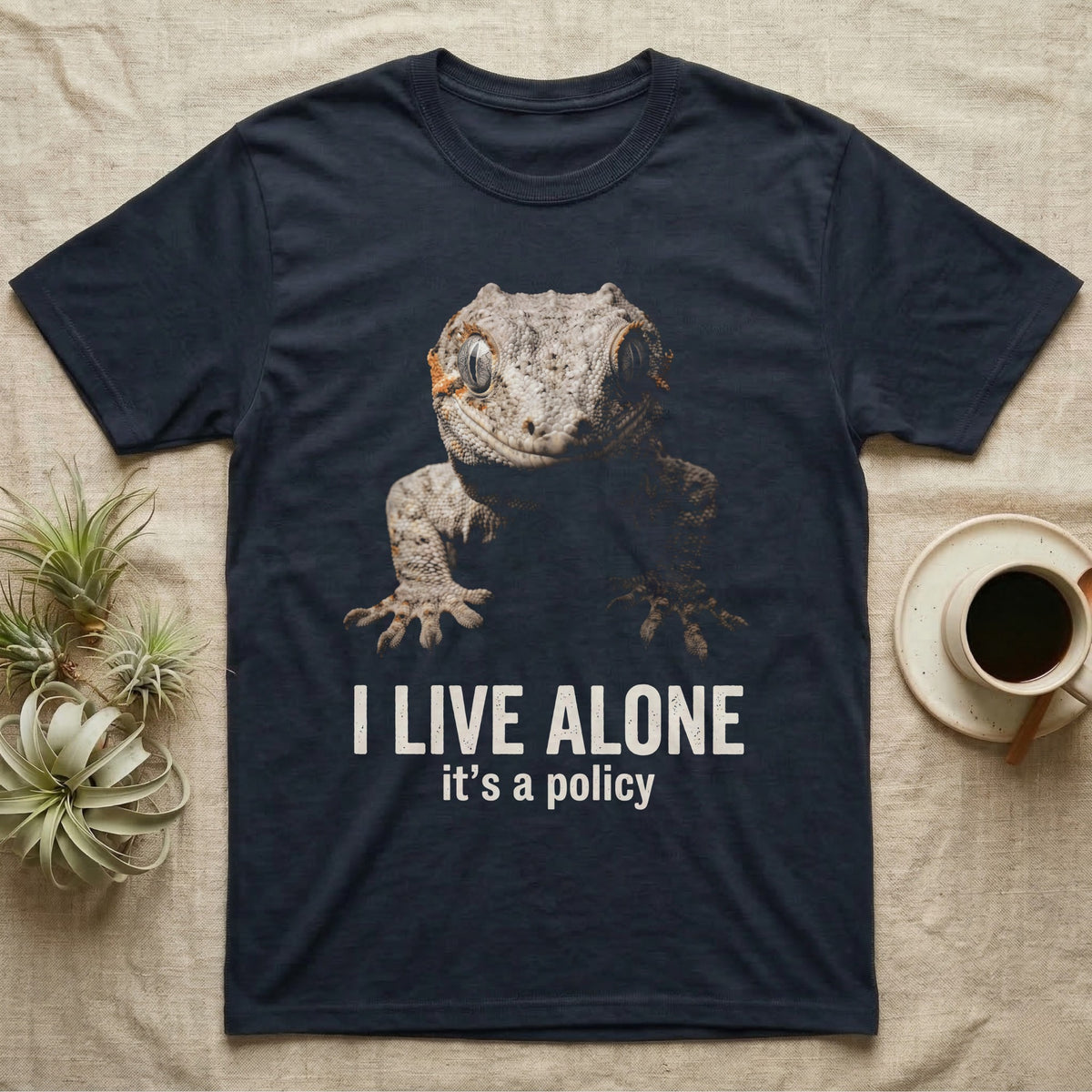 Deadpan photographic mugshot of a gargoyle gecko reaching toward the camera above the distressed text I Live Alone, it's a policy. — shown on a Navy tee.