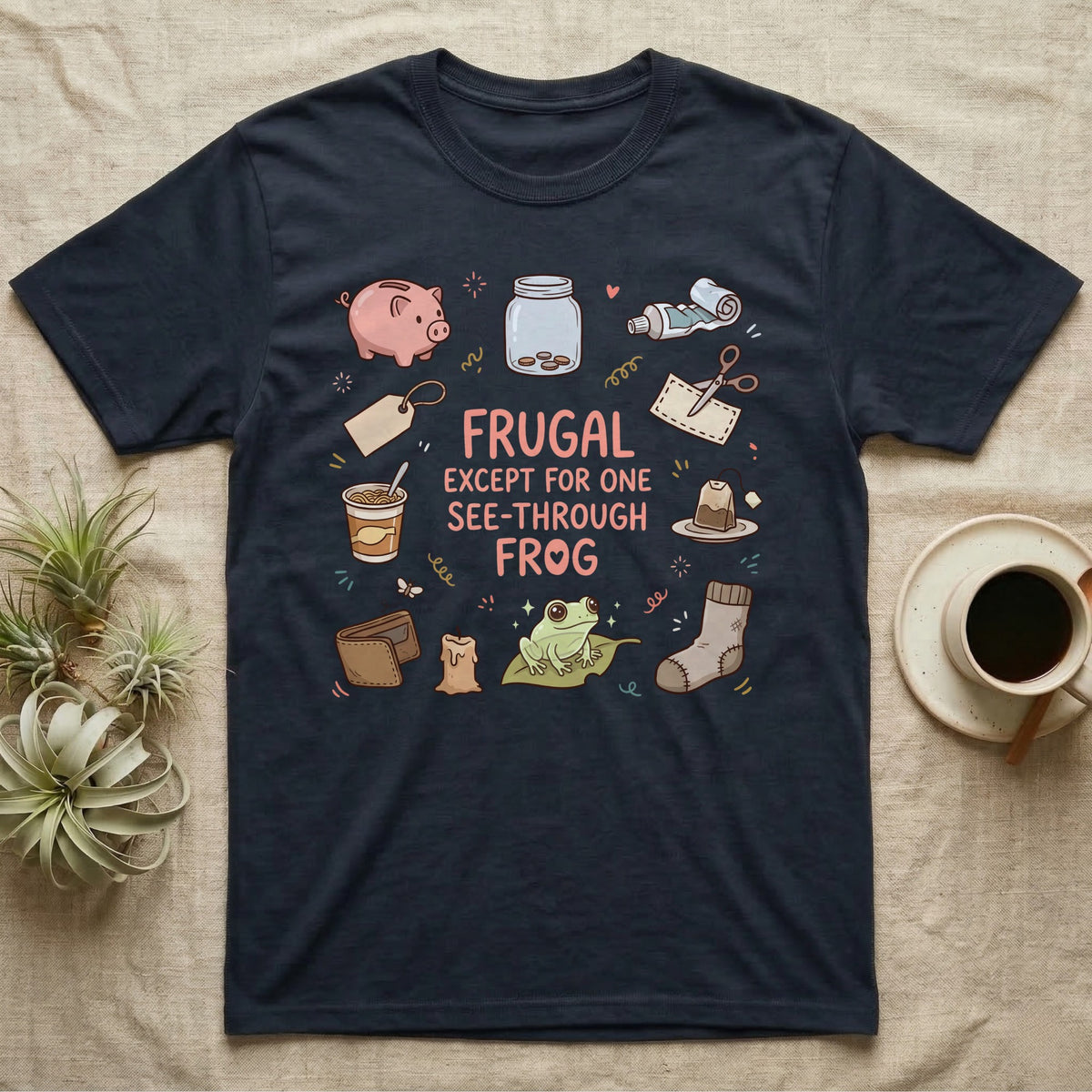 Glass Frog Frugal T-Shirt in Navy — Cartoon glass frog on a leaf under the words Frugal except for one see-through frog, ringed by a piggy bank, coin jar, coupons and other thrifty things
