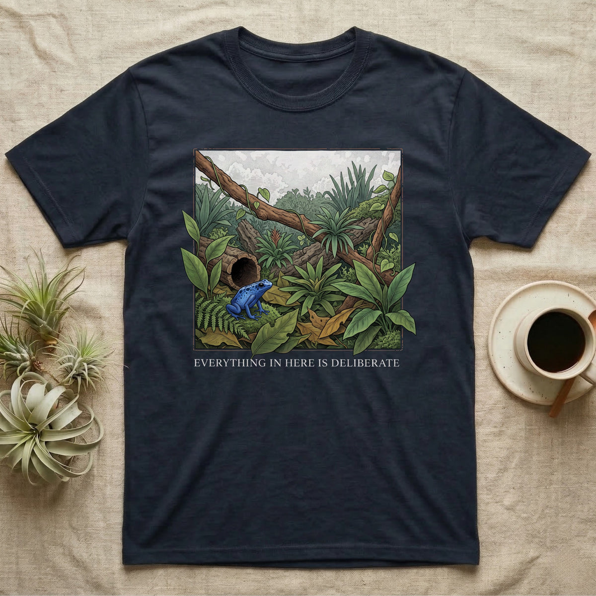 Dart Frog Bioactive Vivarium T-Shirt in Navy — Illustrated panel of a cobalt dart frog in a layered planted vivarium, leaves crossing the inked border.