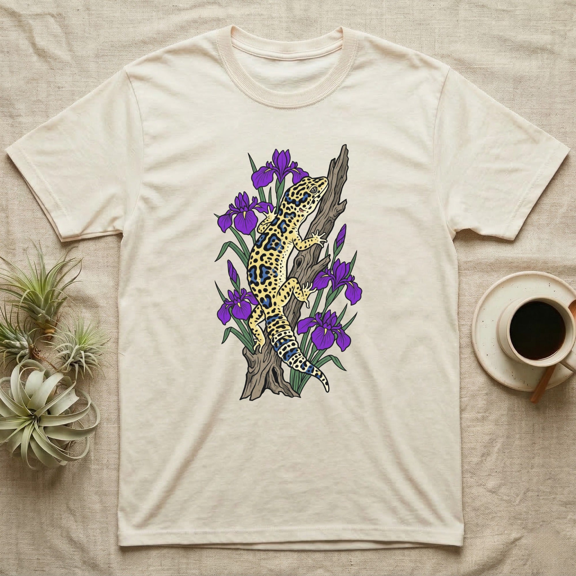 Leopard gecko on a branch with purple irises, on a cream t-shirt.