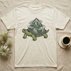 Cream t-shirt with illustration of a turtle carrying a mountain on its shell.