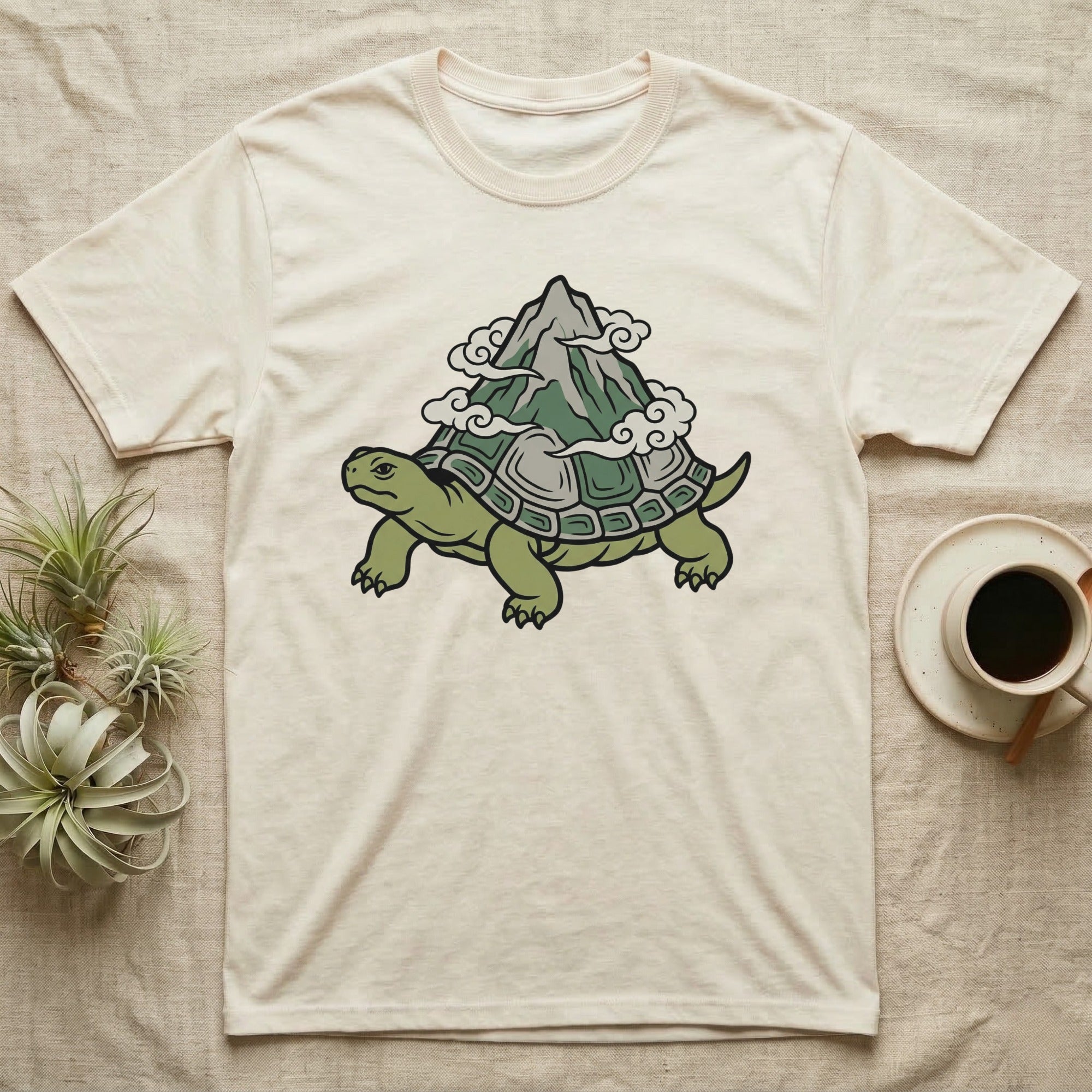 Cream t-shirt with illustration of a turtle carrying a mountain on its shell.