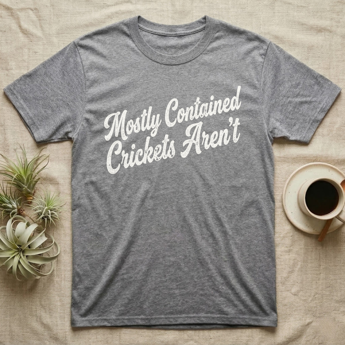 Reptile Cricket Escape T-Shirt in Sport Grey — Distressed off-white 1970s brush script reading Mostly Contained, Crickets Aren't, climbing a diagonal on charcoal grey