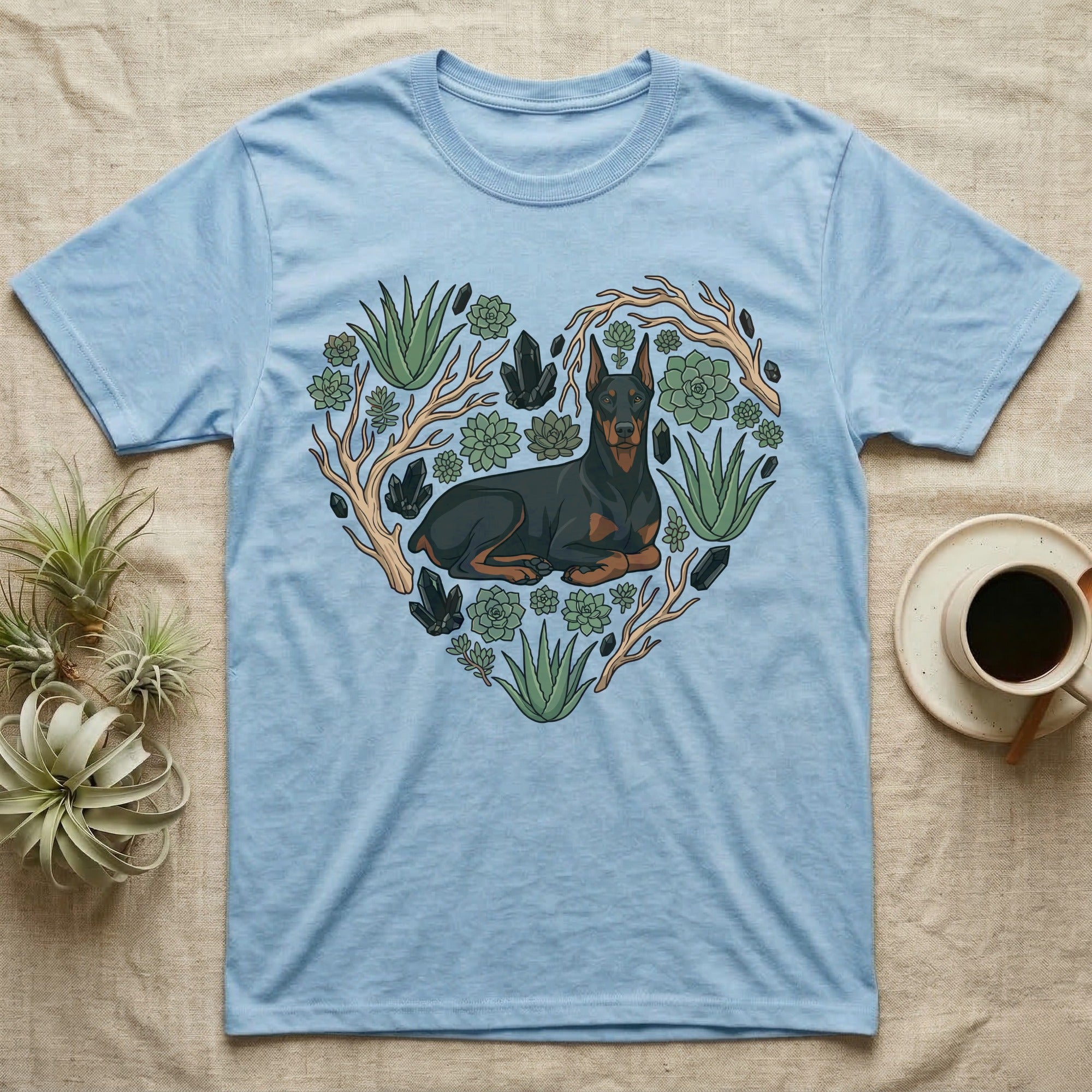 Light blue t-shirt with a Doberman Pinscher in a heart shape surrounded by succulents and crystals.