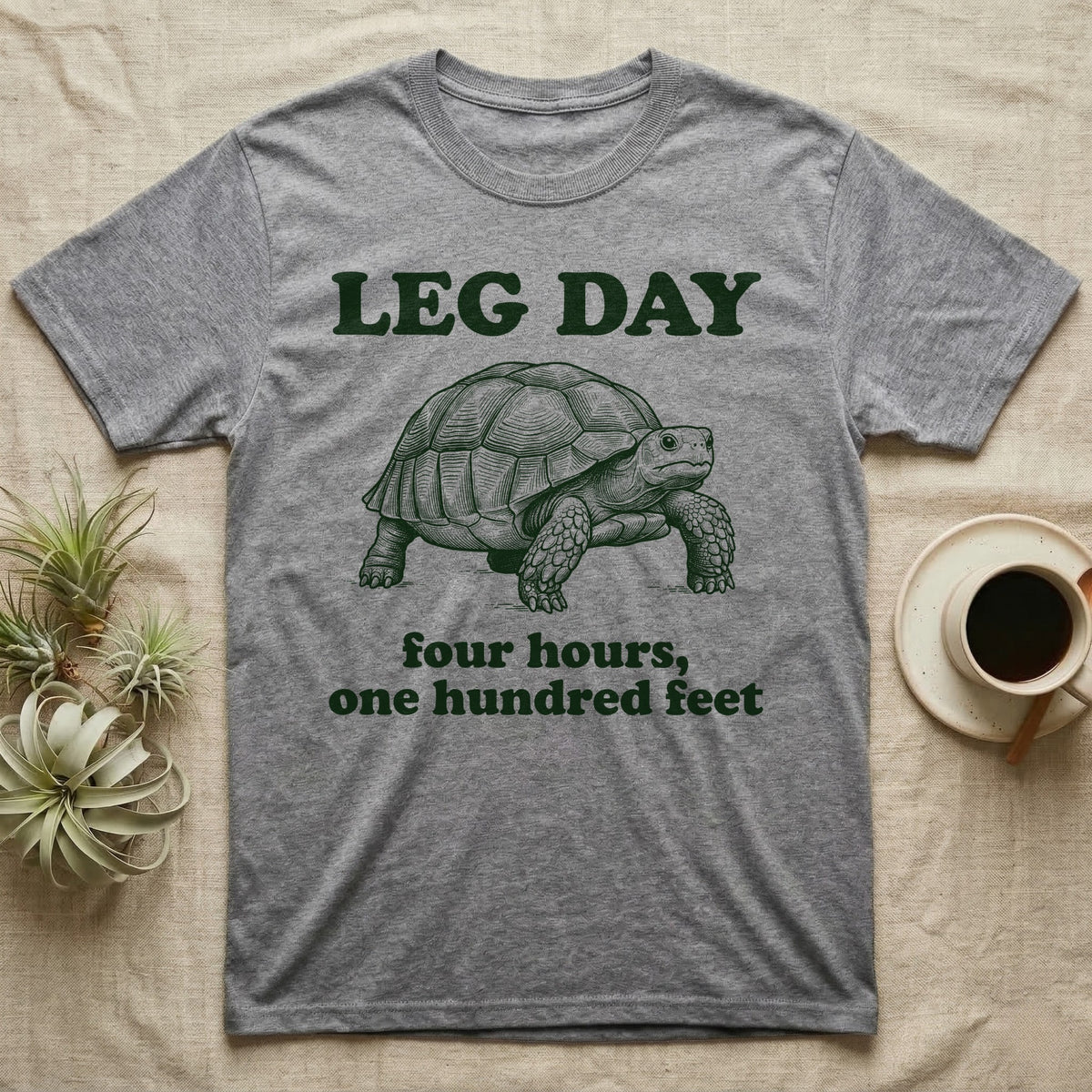 Sulcata Tortoise Leg Day T-Shirt in Sport Grey — Engraved sulcata tortoise in deep green ink beneath the words LEG DAY, with four hours, one hundred feet below.
