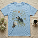 Jumping Spider Home Range T-Shirt in Light Blue — Woodcut-style illustration of a regal jumping spider perched on a saw palmetto blade with pines behind, no on-shirt text.