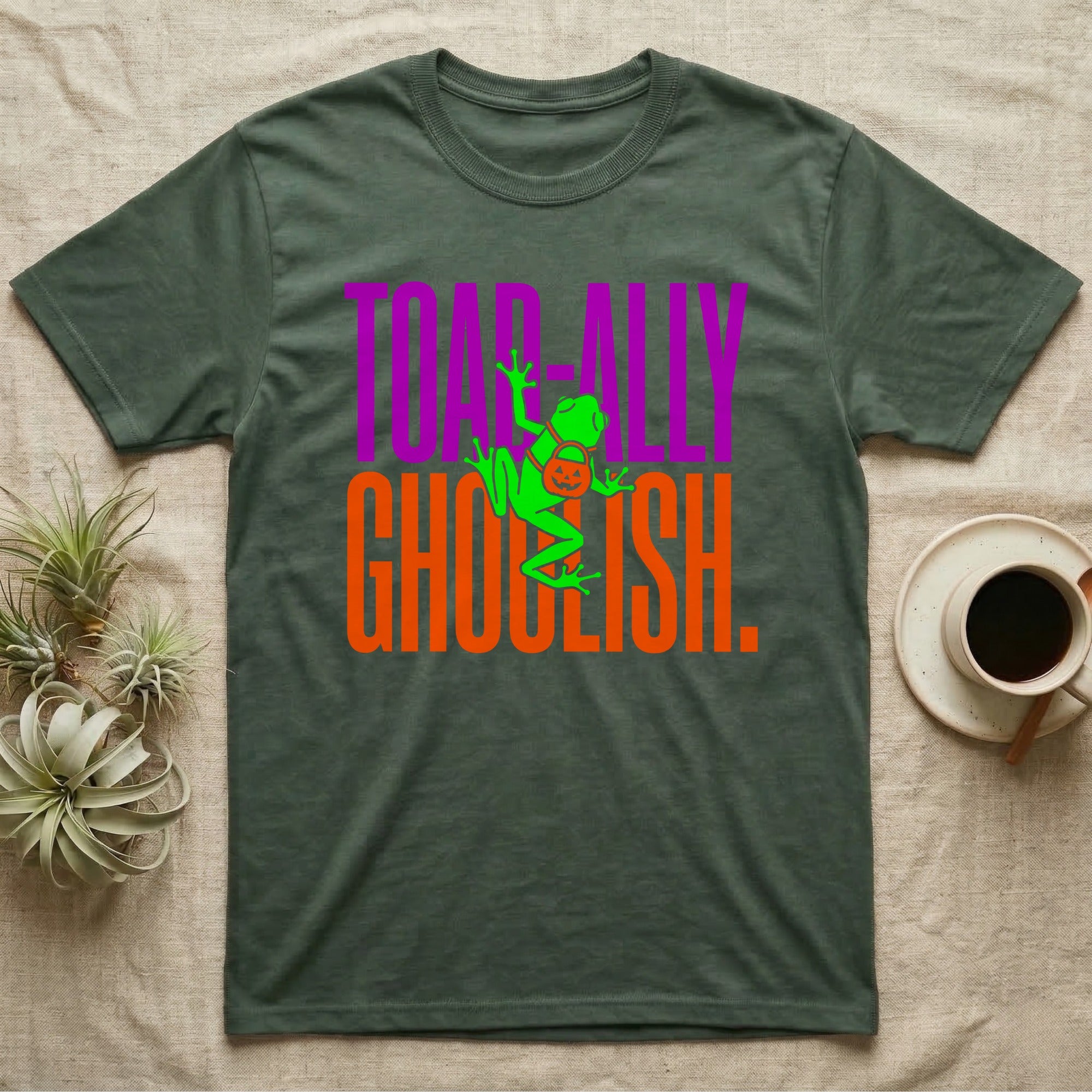 Tree Frog Toad-ally Ghoulish T-Shirt in Military Green — Neon green tree frog with a pumpkin pail clinging across stacked text, "Toad-ally Ghoulish."