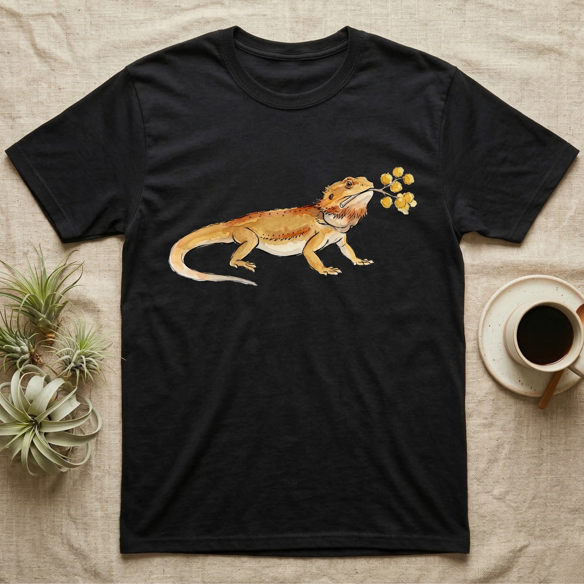 Bearded Dragon Blossom T-Shirt in Black — Watercolor illustration of an ochre bearded dragon holding a golden wattle blossom sprig, on a dark grey t-shirt.