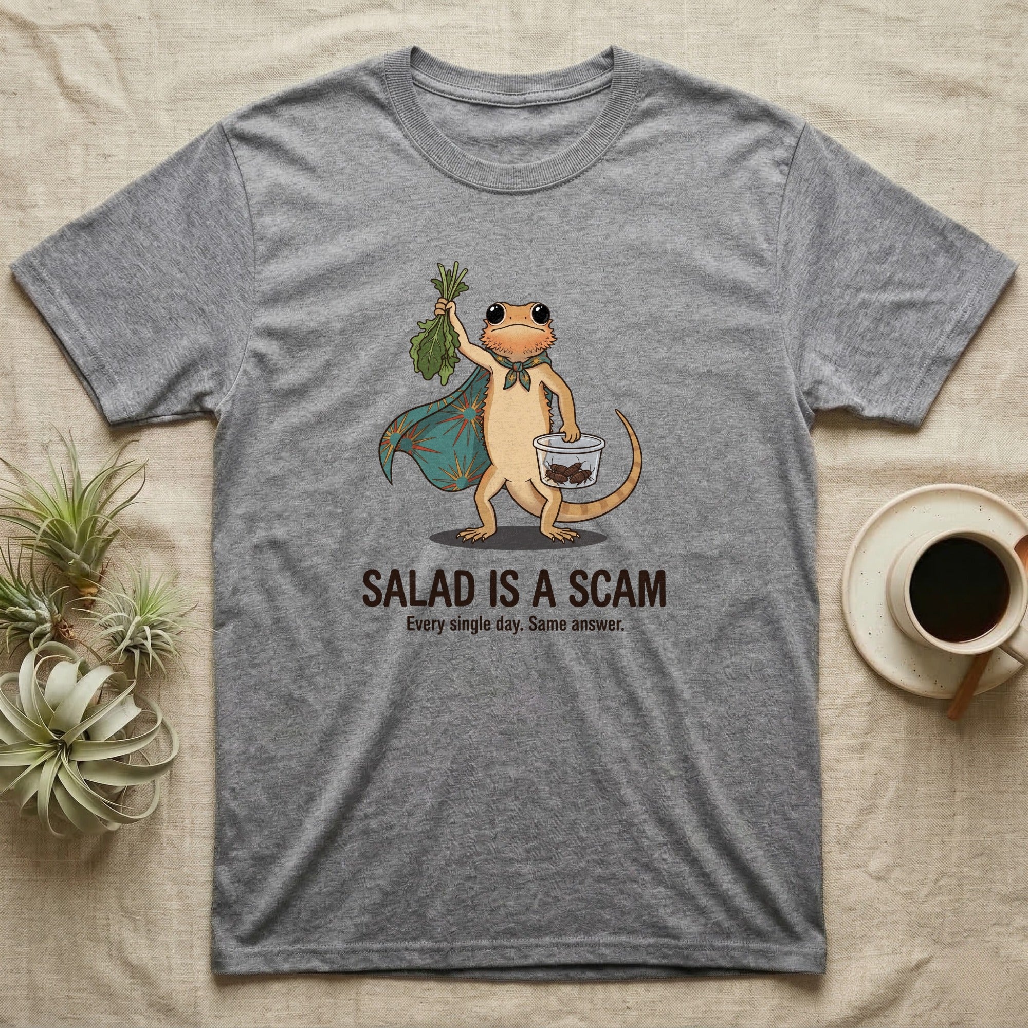 Bearded Dragon Salad Scam T-Shirt in Sport Grey — Storybook-cartoon bearded dragon holding wilted greens at arm's length and a tub of roaches, captioned "Salad Is a Scam".