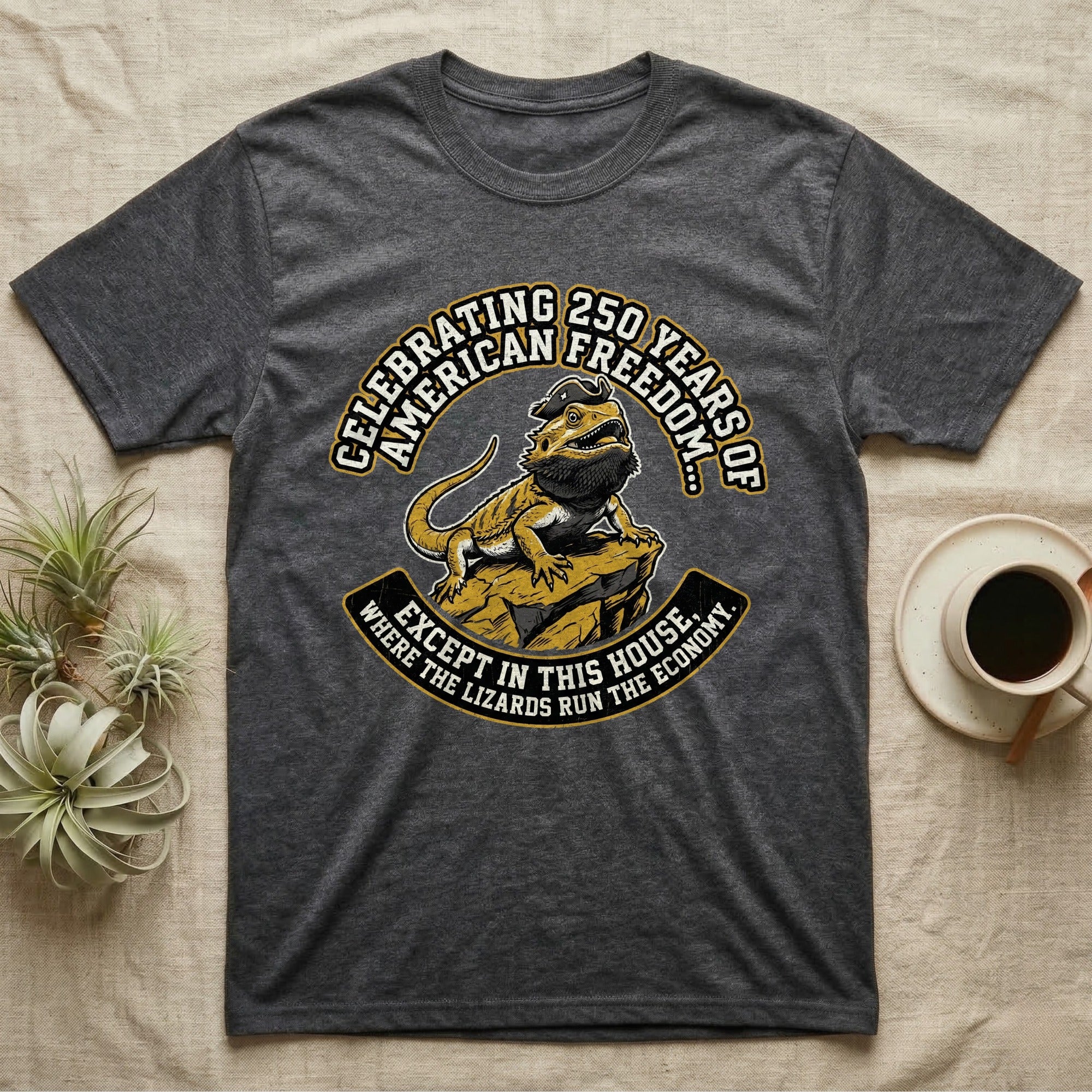 Bearded Dragon 1776 T-Shirt in Dark Heather — Bold woodcut tee of a bearded dragon in a tricorn hat black-bearding on a rock, gold and cream banner reading the lizards run the economy.