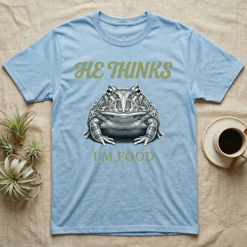 Pacman Frog He Thinks I'm Food T-Shirt in Light Blue — Engraved white-line illustration of a pacman frog staring straight ahead below retro script lettering reading HE THINKS.