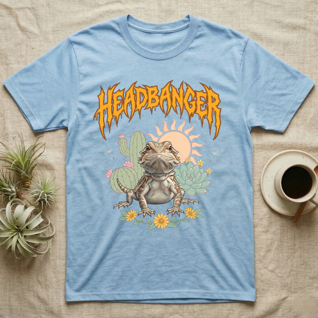 Central Bearded Dragon Feral T-Shirt in Light Blue — Baby bearded dragon in a pastel desert scene under a spiky amber metal wordmark reading HEADBANGER.