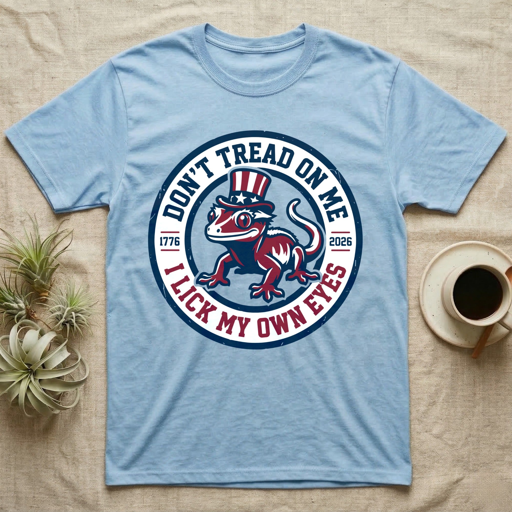 Crested Gecko 1776 T-Shirt in Light Blue — Distressed crest of a crested gecko in a top hat with text Don't Tread On Me and I Lick My Own Eyes.
