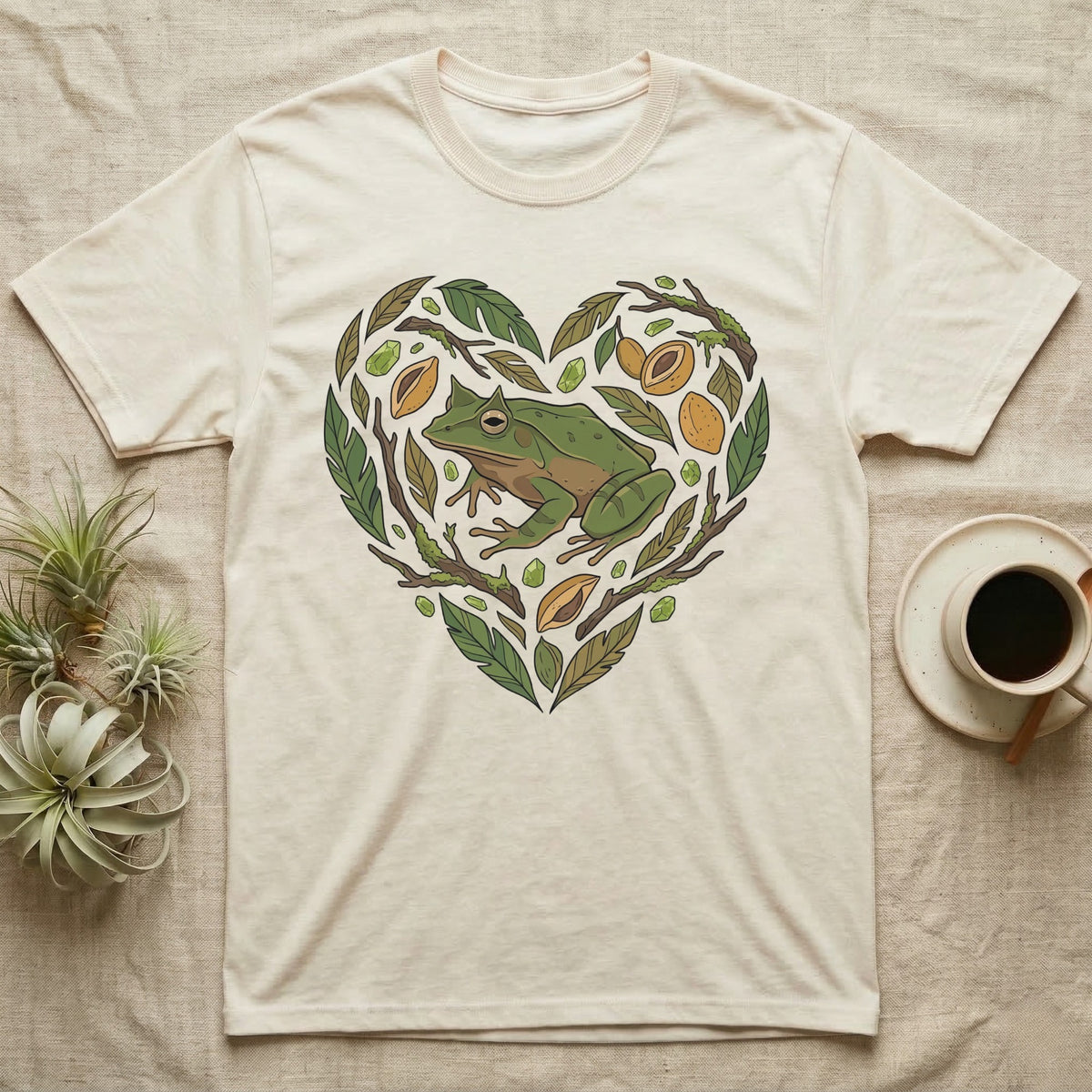 Cream t-shirt with a green frog inside a heart-shaped design of leaves and fruit.