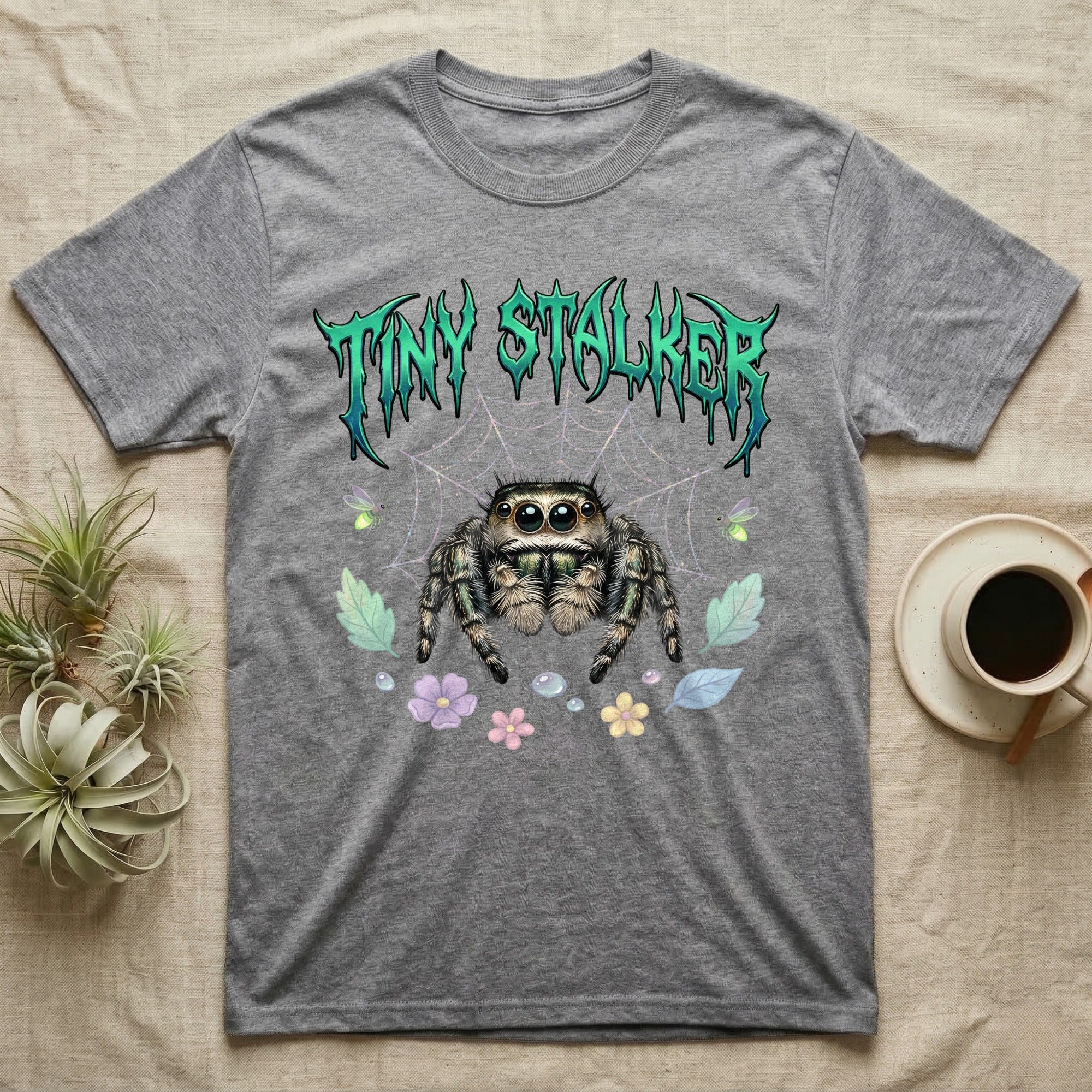 Regal Jumping Spider Feral T-Shirt in Sport Grey — Fuzzy jumping spider with huge eyes in a pastel garden under a spiky iridescent-teal metal wordmark reading TINY STALKER.