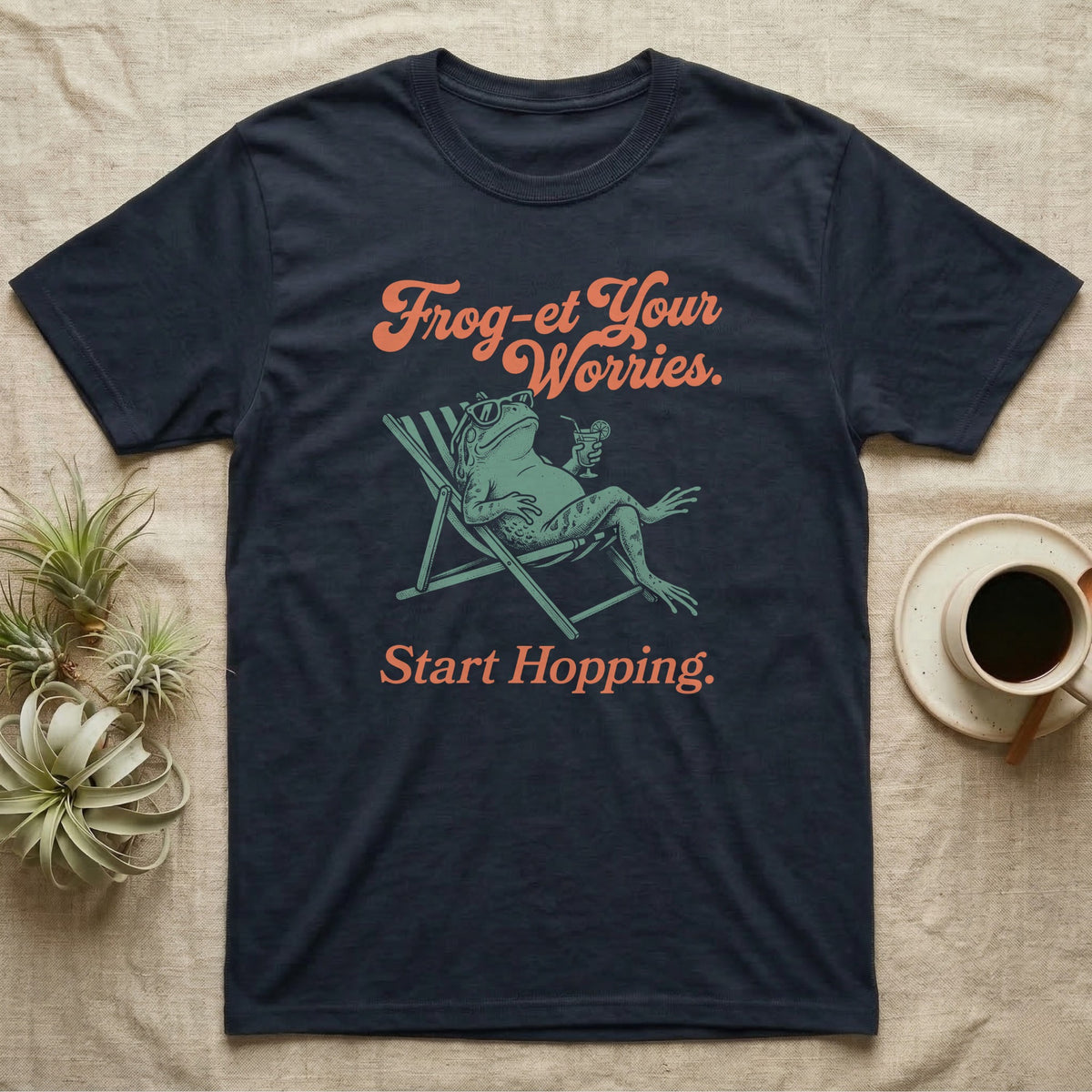 Cane Toad Sun Lounger T-Shirt in Navy — Illustrated cane toad reclining in a beach chair with sunglasses and a cocktail, coral script reading Frog-et Your Worries Start Hopping.