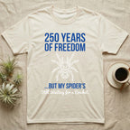 Tarantula Waiting For Cricket Tee in Natural — Minimalist geometric tee with a low-poly white tarantula and blue text reading 250 Years Of Freedom but my spider's still waiting for a cricket.